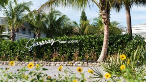 A sign for 'Geaspray SURF LODGE' with a view of palm trees and a building in the background. - Seaspray Surf Lodge (Vero Beach)