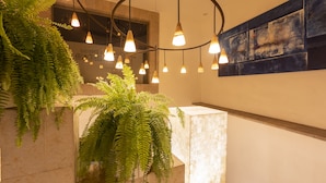 A staircase with a circular light fixture, stone walls, and green plants. - Hotel Boutique Casa San Diego (Morelia)