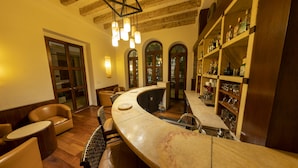 A bar area with a curved counter, leather seating, and wooden shelves with bottles. - Hotel Boutique Casa San Diego (Morelia)