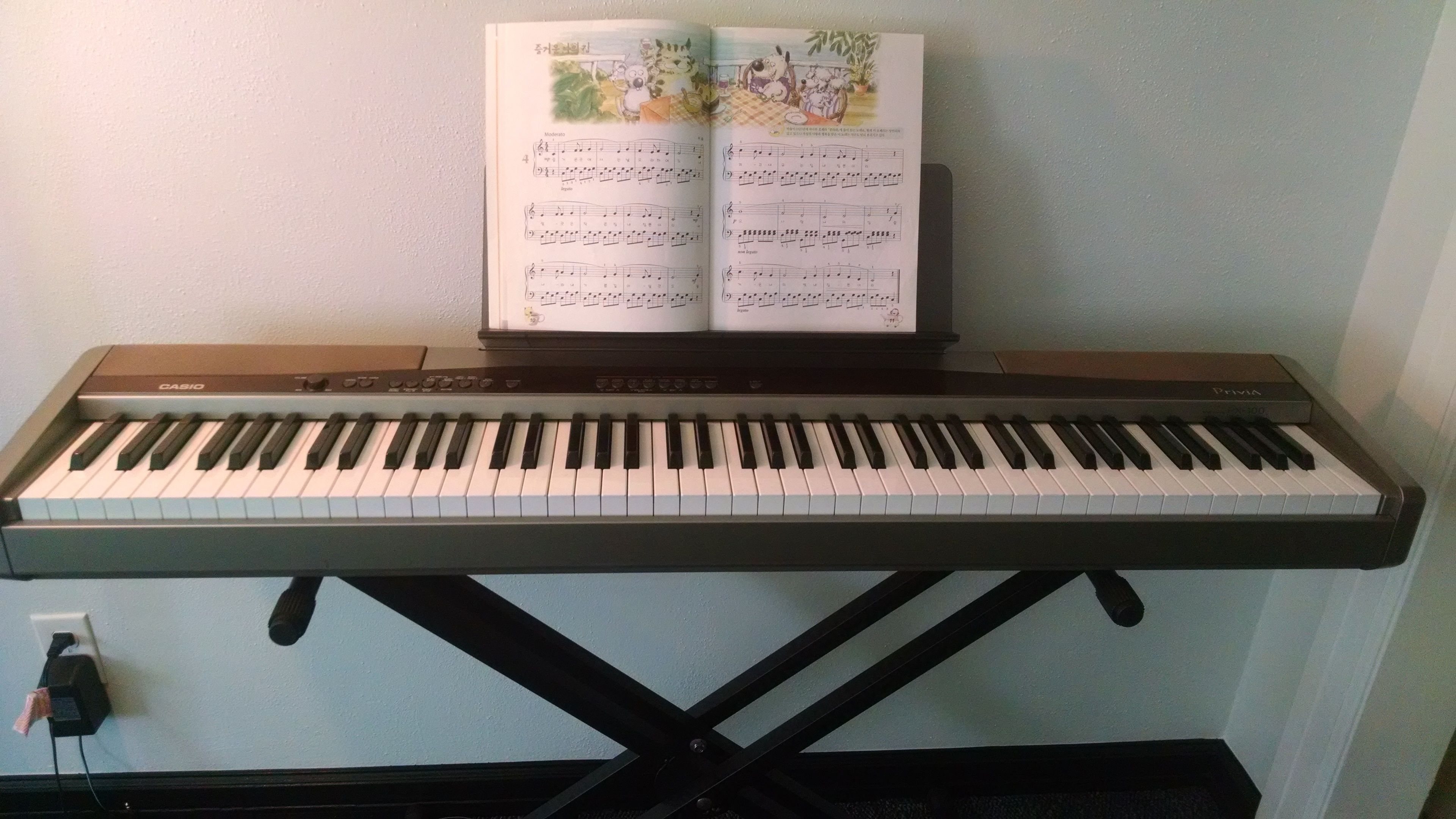 A Casio Privia keyboard with sheet music on top.