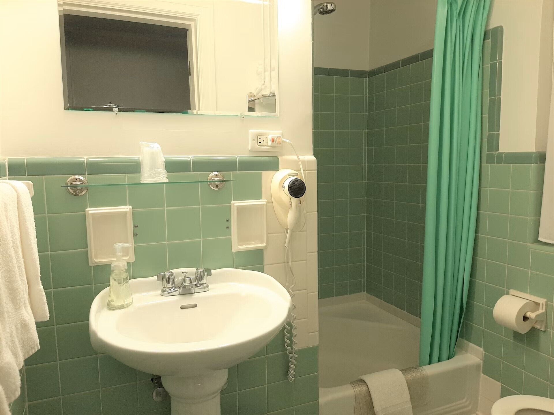 Un baño con lavamanos, espejo, ducha e inodoro.