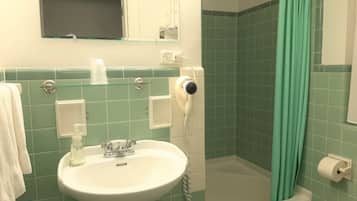 Un baño con lavamanos, espejo, ducha e inodoro.