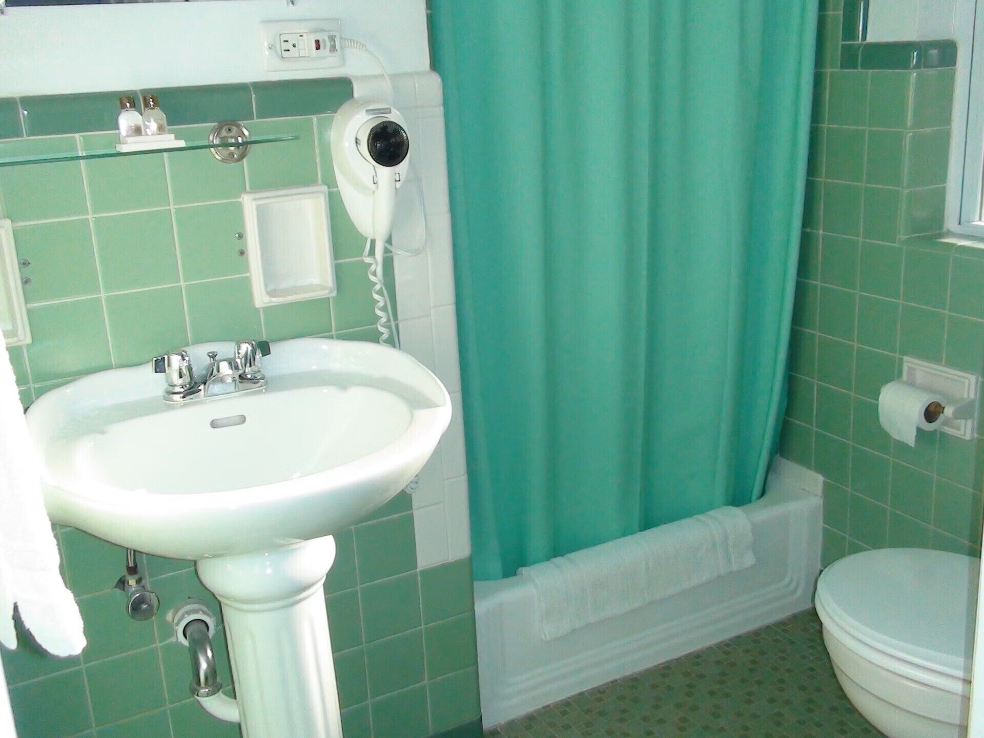 Un baño con lavamanos blanco, secador de pelo, inodoro y bañera.