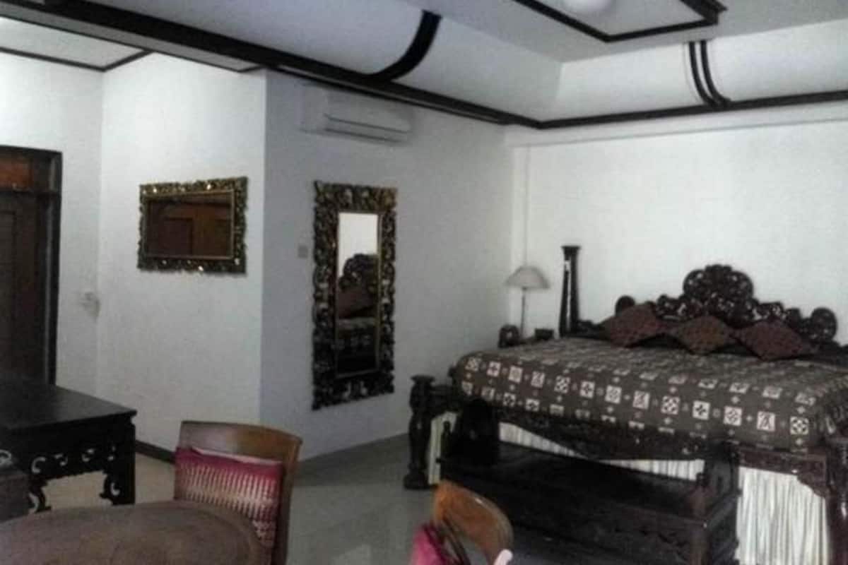 A room with a bed, a chair, a table, and a mirror.
