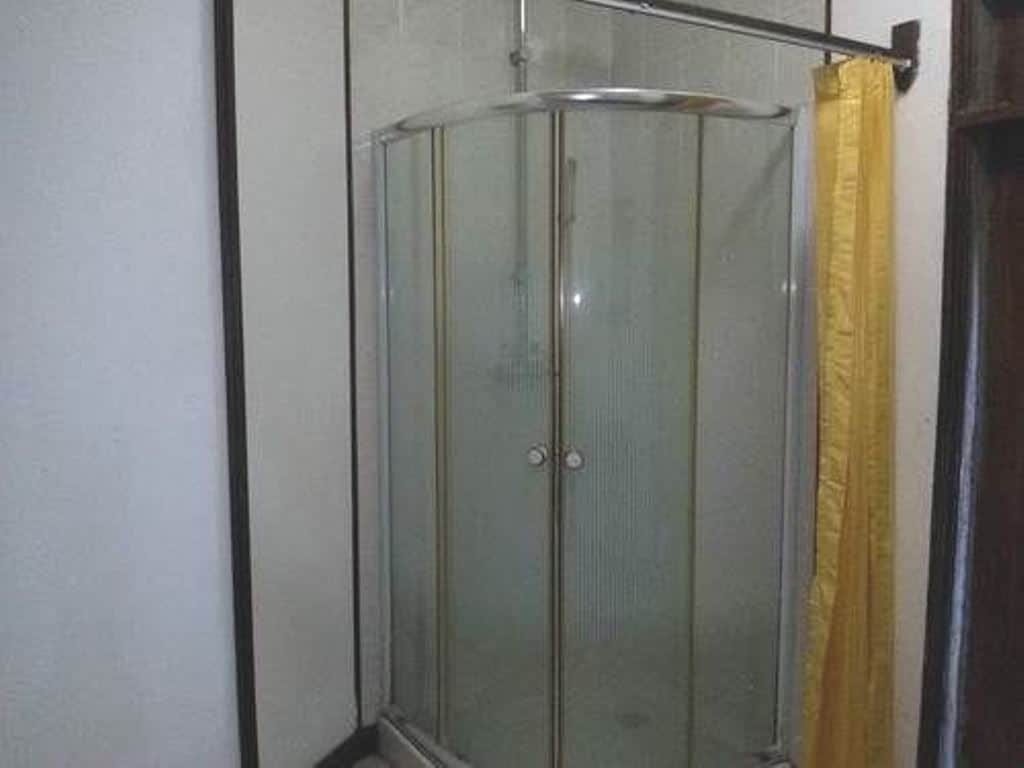 A glass-enclosed shower stall with a yellow curtain.