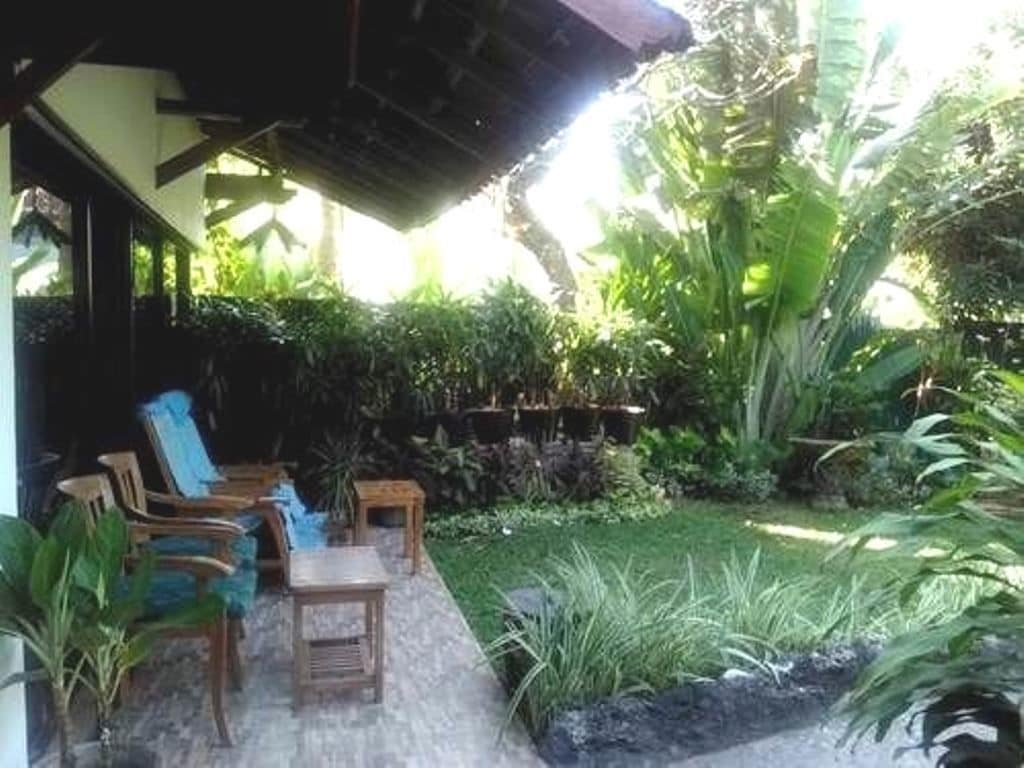 An outdoor seating area with wooden furniture and a variety of plants.