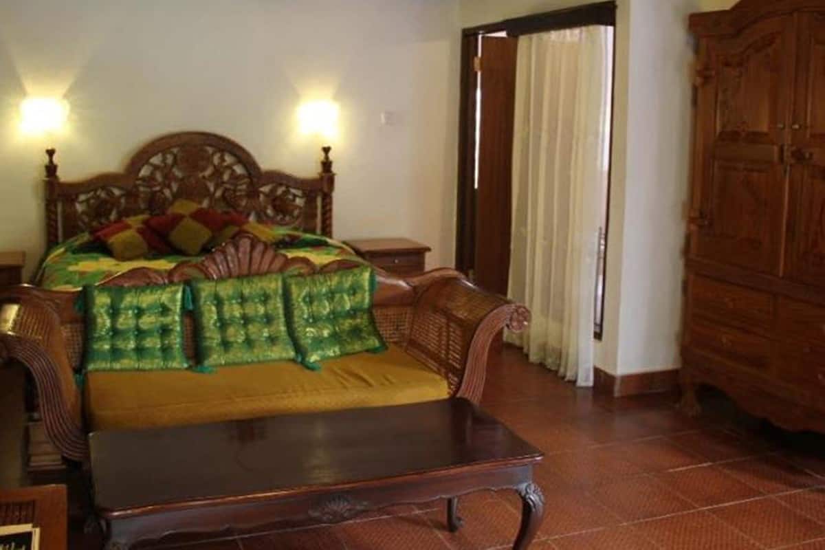 A traditional room with a wooden bed, a wooden nightstand, a wooden wardrobe, and a tiled floor.