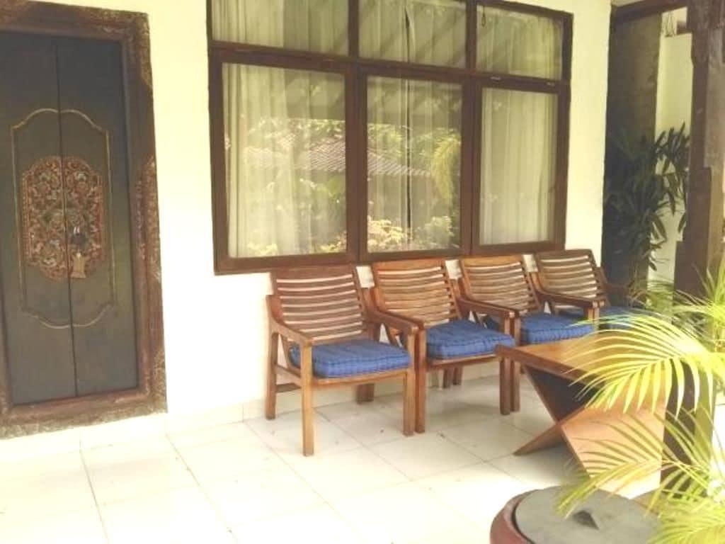 A room with a large window, a wooden door, and a seating area with blue cushioned chairs.