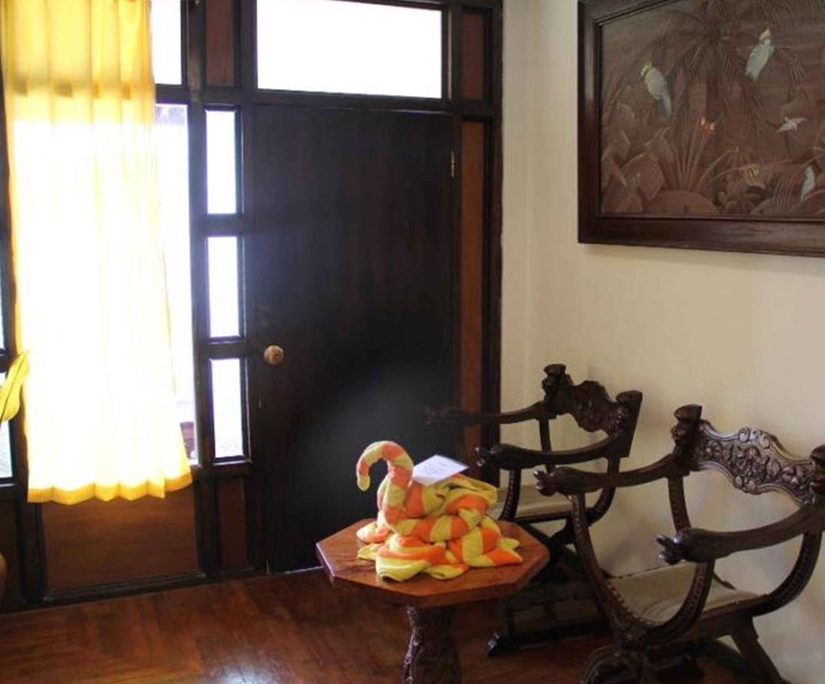 Una habitación con una puerta de madera, un cuadro en la pared y una mesa con un peluche.