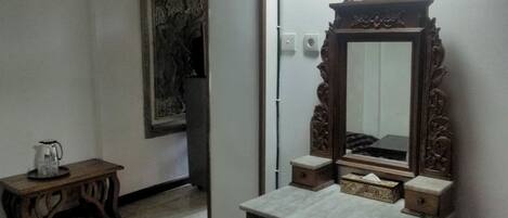 Una habitación con un aparador de madera, un espejo y una obra de arte enmarcada en la pared.