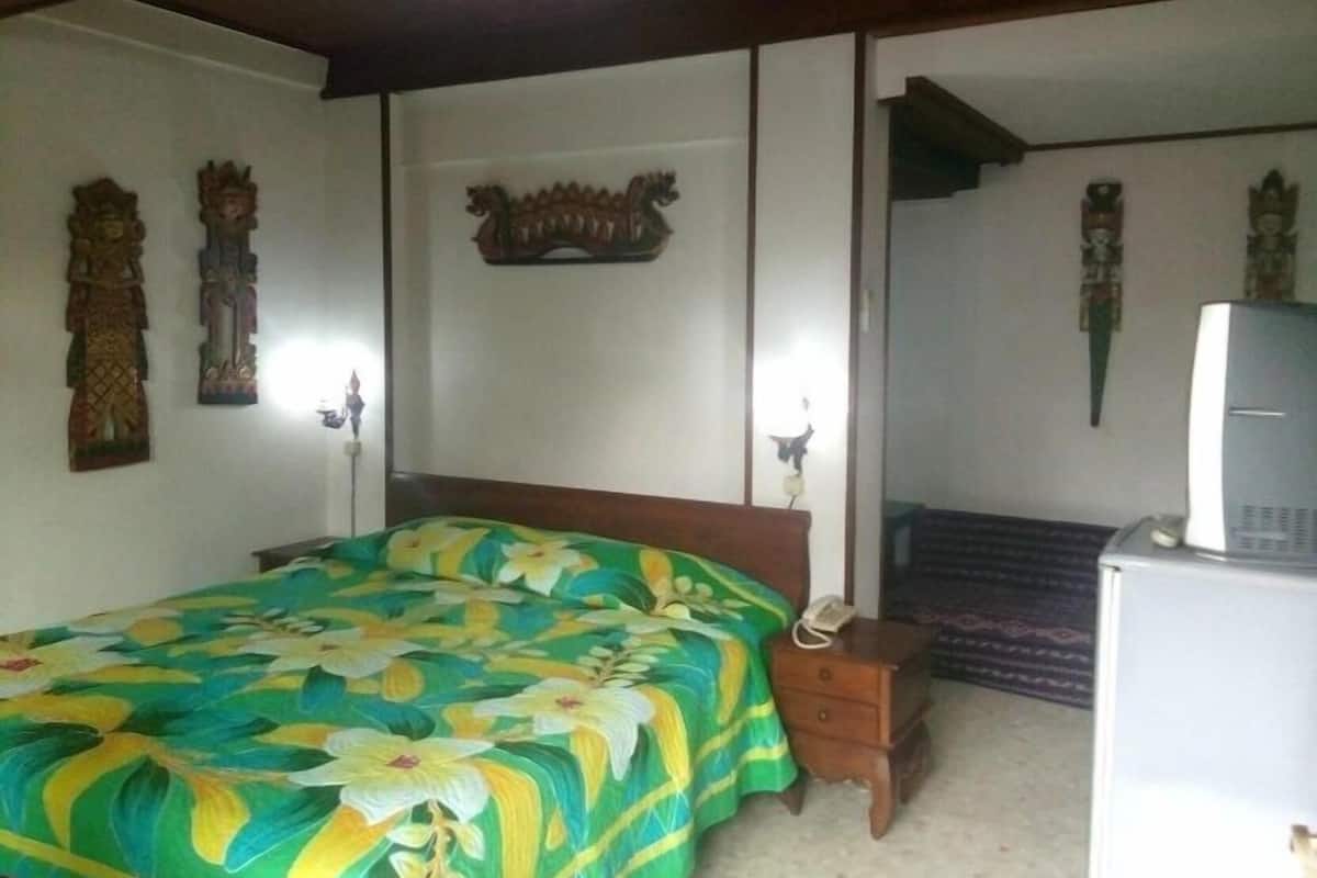 A bedroom with a bed, a nightstand, a desk with a computer, and decorative wall art.