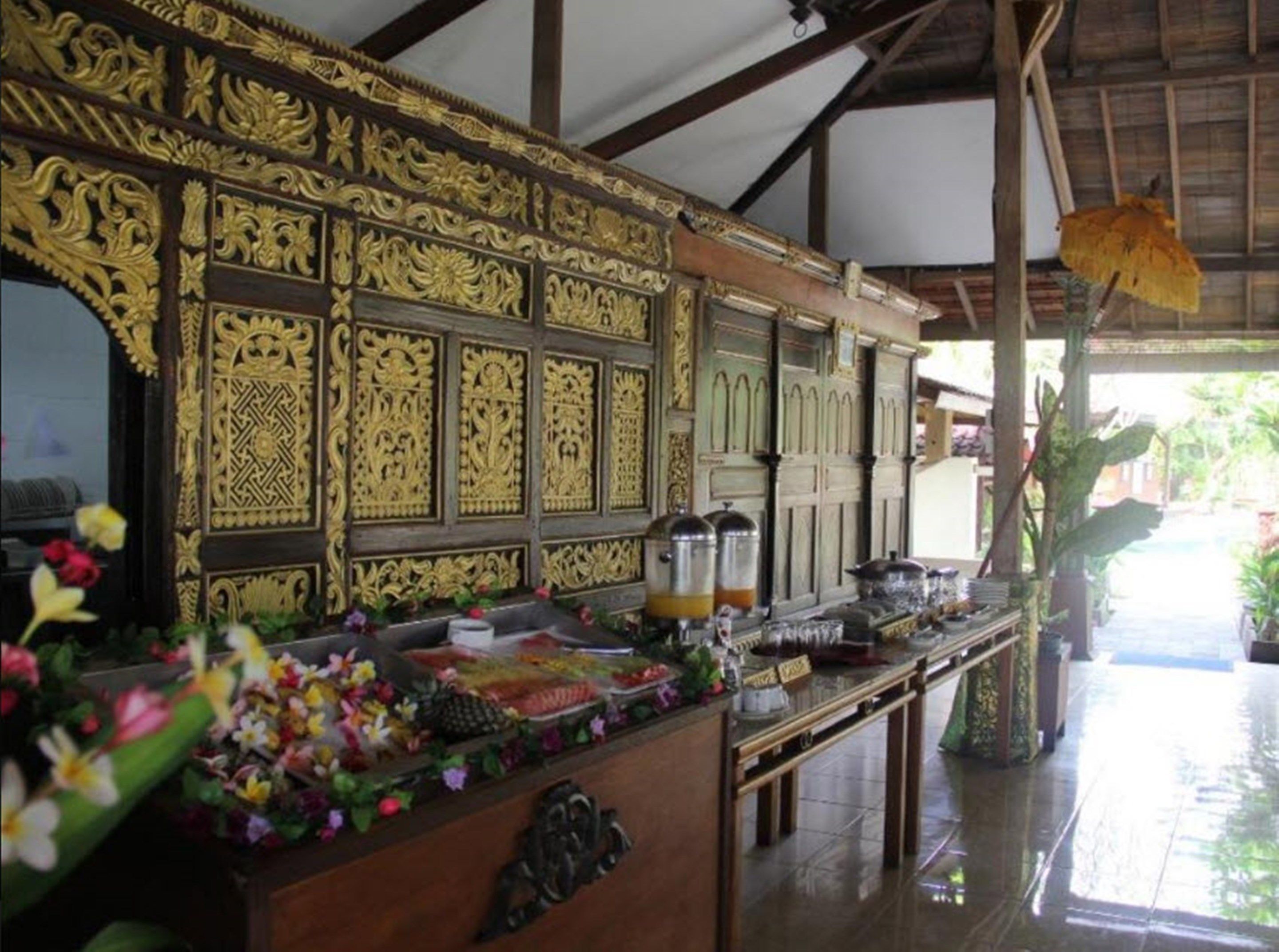A traditional wooden structure with intricate carvings, a counter with various items, and a thatched roof.