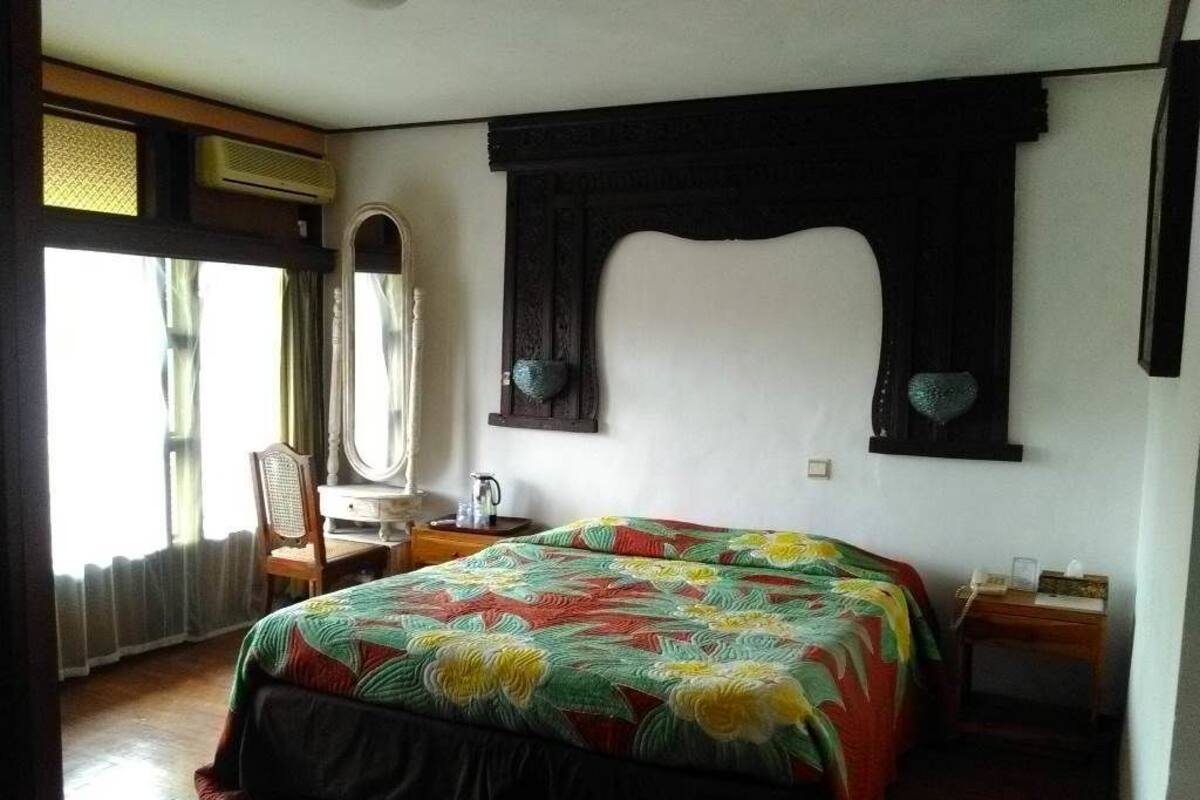 A bedroom with a bed, a desk, a chair, and a window.