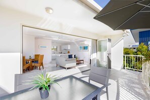 A modern apartment with a balcony, a dining area, and a kitchen. - Noosa River Palms (Noosaville)