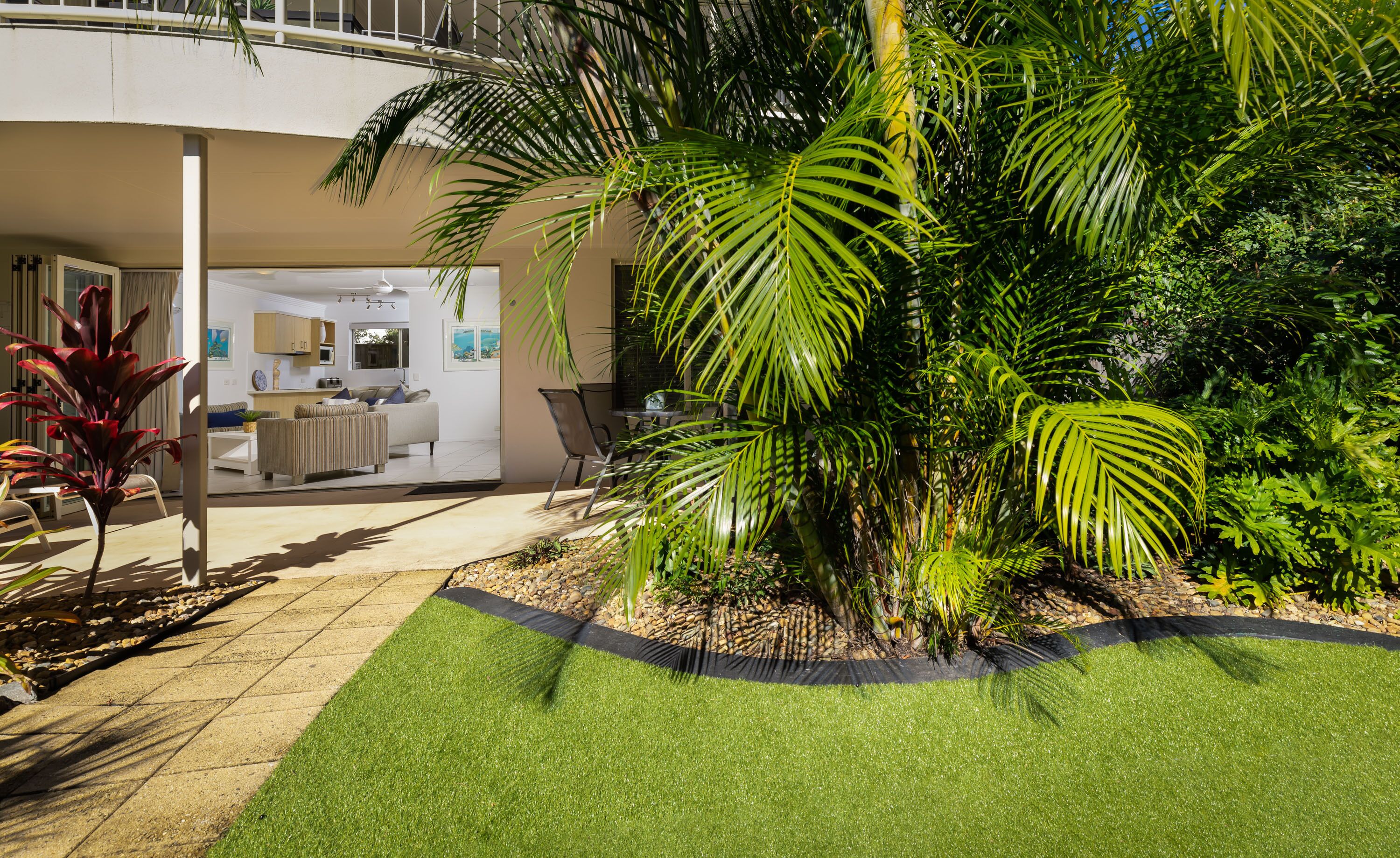 A modern house with a patio area, a dining area, and a kitchen visible through an open door.