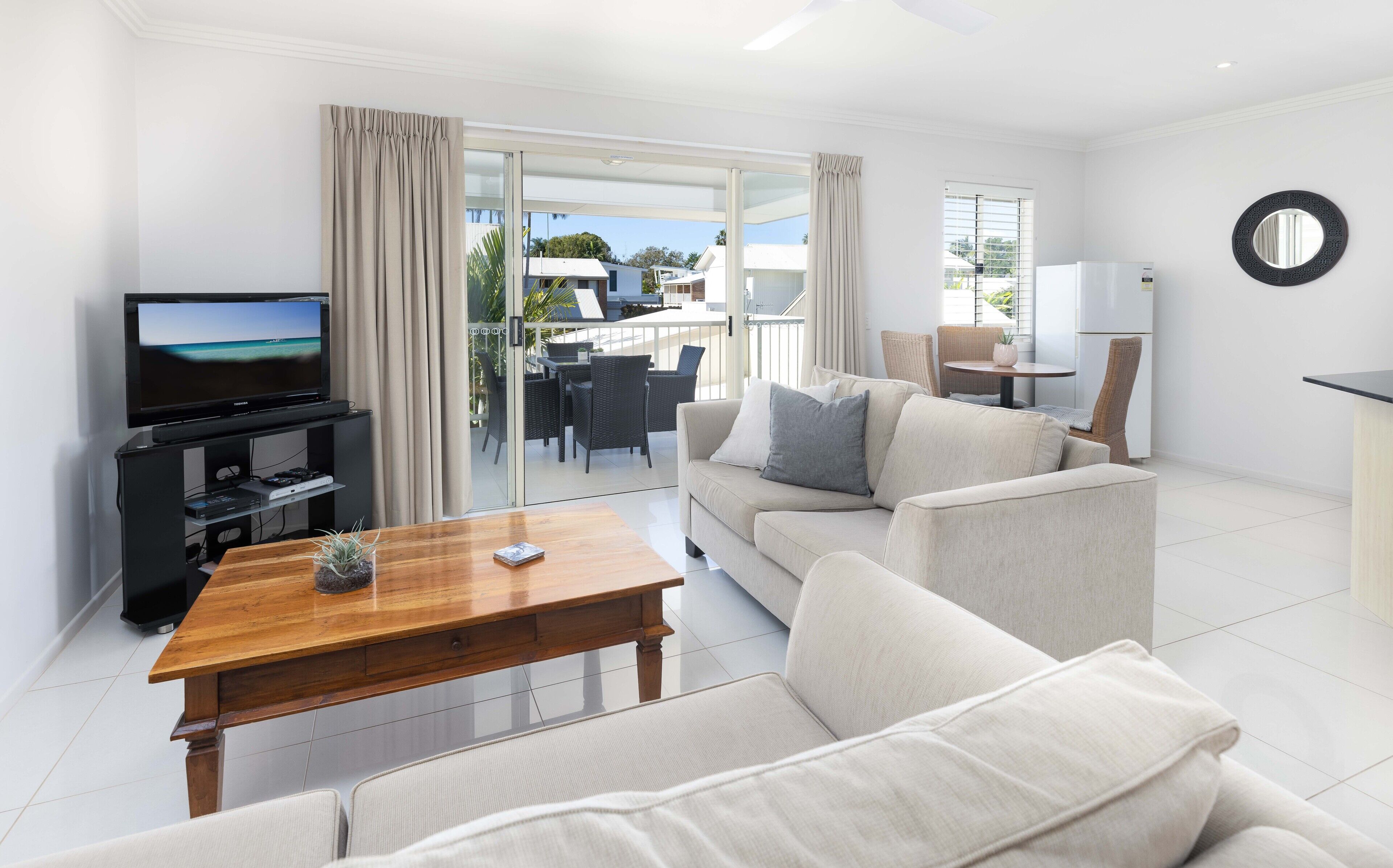 A modern living room with a flat-screen TV, a wooden coffee table, and a beige sofa.