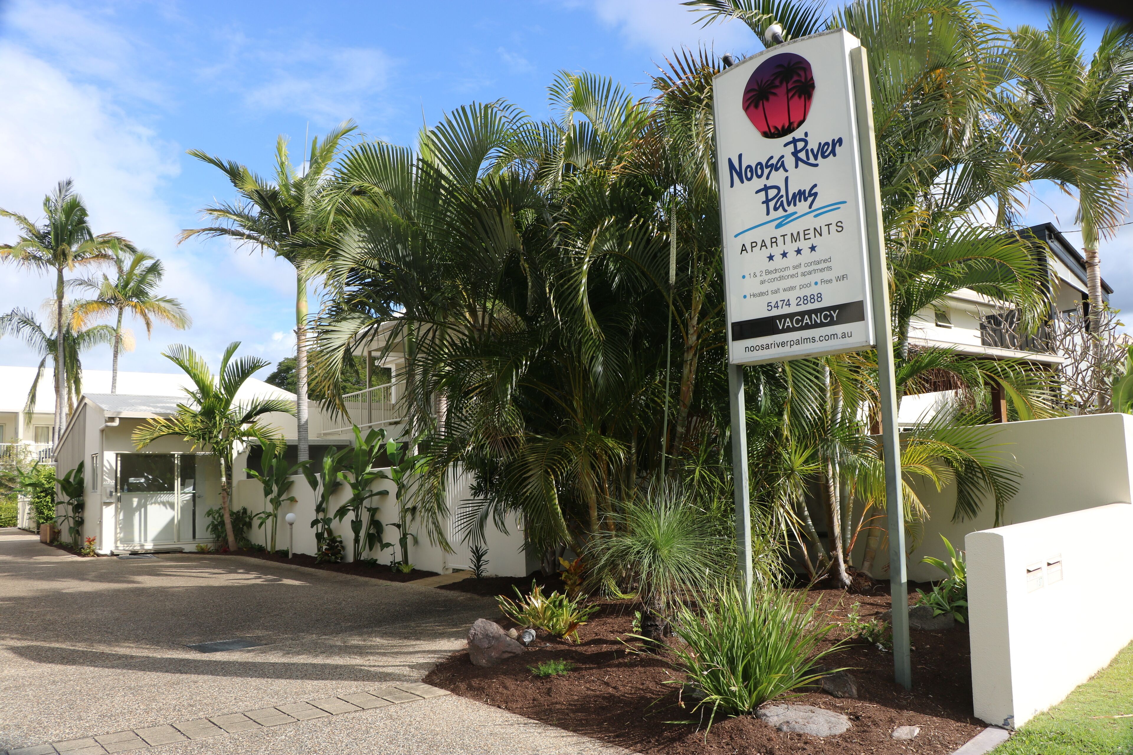 A sign for Noosa River Palms Apartments with a 4.5-star rating, 18 units, self-contained, and a 2-bedroom option.