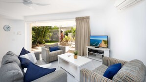 A modern living room with a sofa, armchairs, a coffee table, and a TV.