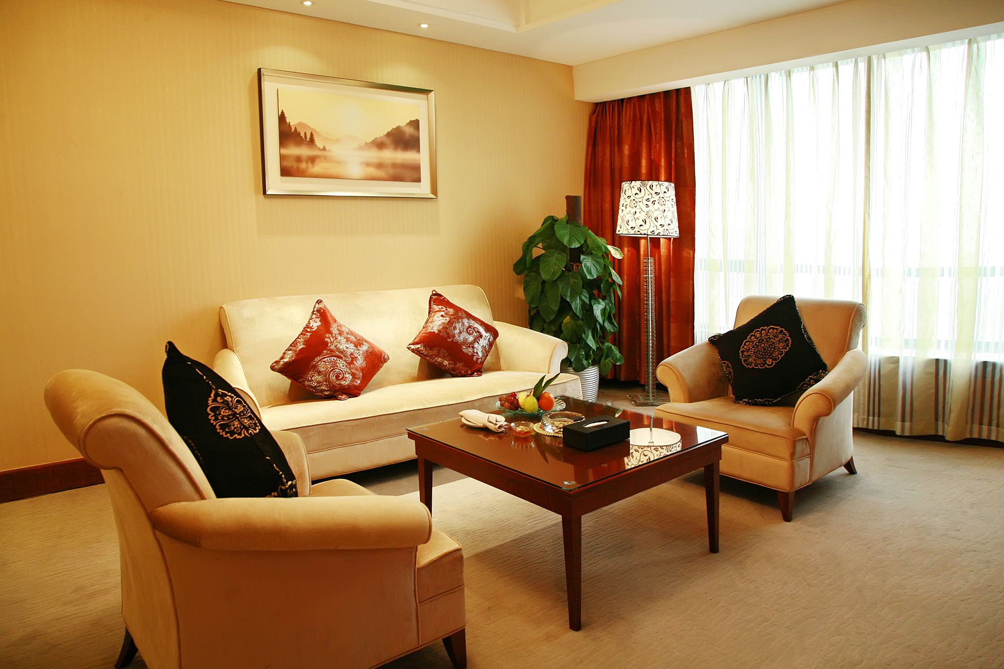 Una sala de estar bien iluminada con un sofá color beige, dos sillones, una mesa de centro y un cuadro en la pared.