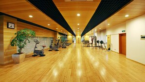 A gym with exercise equipment, wooden floors, and a potted plant. - Grand Barony Zhoushan (Zhoushan)