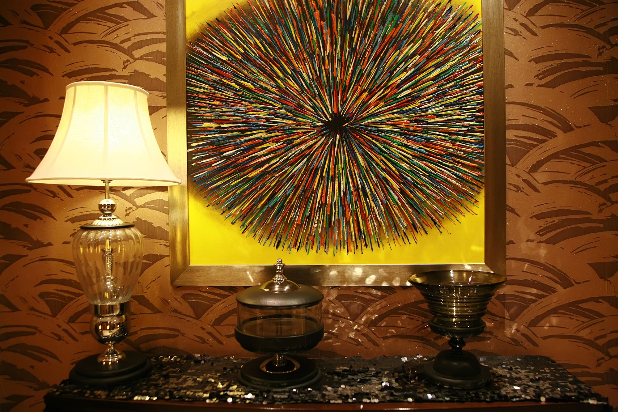 A room with a lamp, a decorative table, and a colorful abstract painting on the wall.