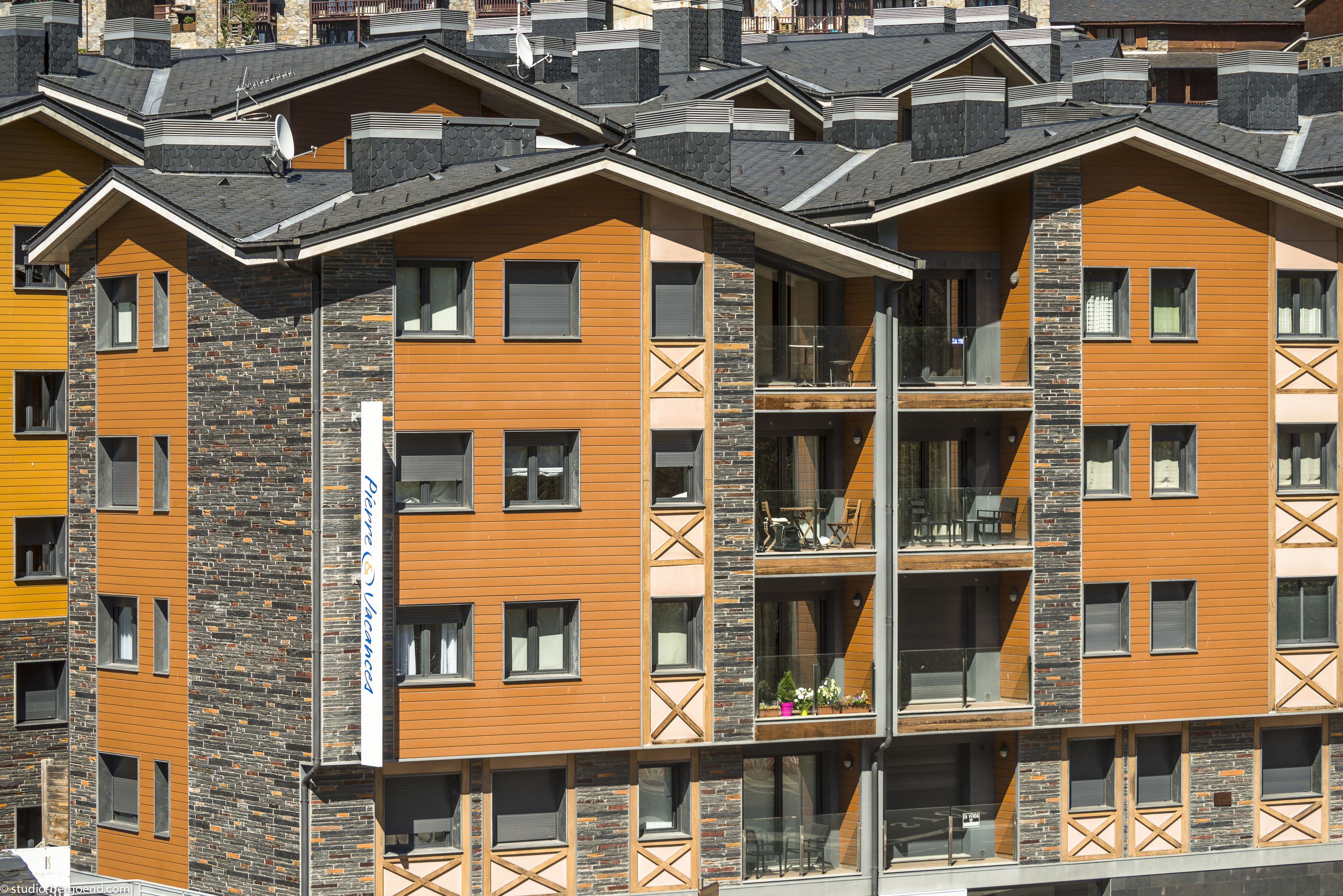 A multi-story building with a modern architectural design, featuring balconies and large windows.