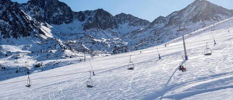 A snowy mountain slope with ski lifts and a clear sky.