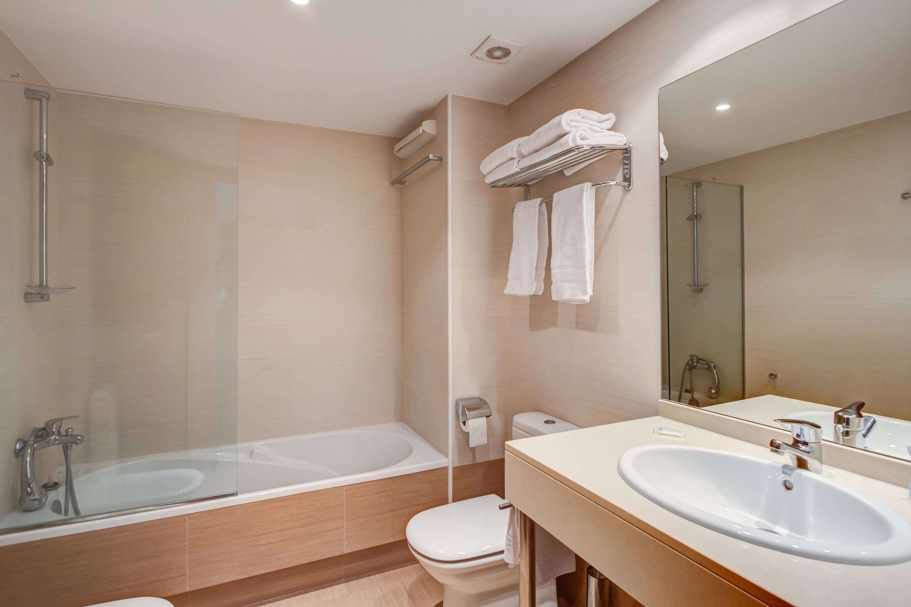 A modern bathroom with a glass-enclosed shower, a bathtub, a toilet, and a vanity with a sink and mirror.