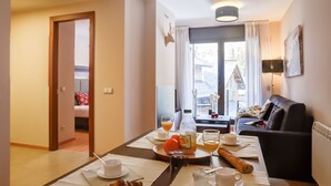 A dining area with a table set for breakfast, a sofa, and a view of the outside. - Pierre & Vacances Andorra El Tarter (El Tarter)
