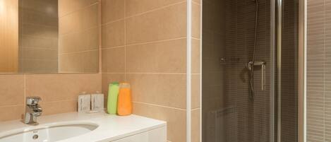 A bathroom with a sink, mirror, and shower.