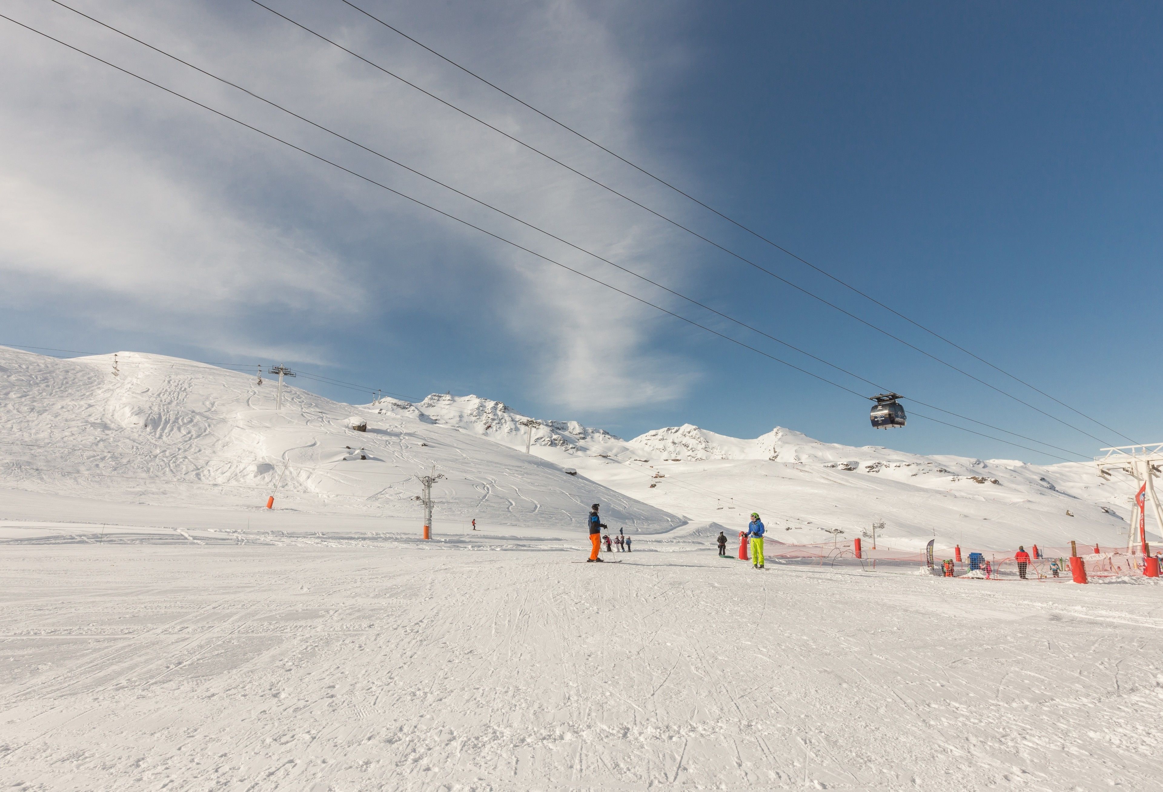 Une piste de ski enneigée, avec des remontées mécaniques et des skieurs.