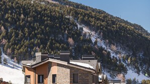 A multi-story hotel with a modern architectural design, featuring a mix of brick and wood exteriors, and a view of a snow-covered mountain. - Pierre & Vacances Andorra El Tarter (El Tarter)