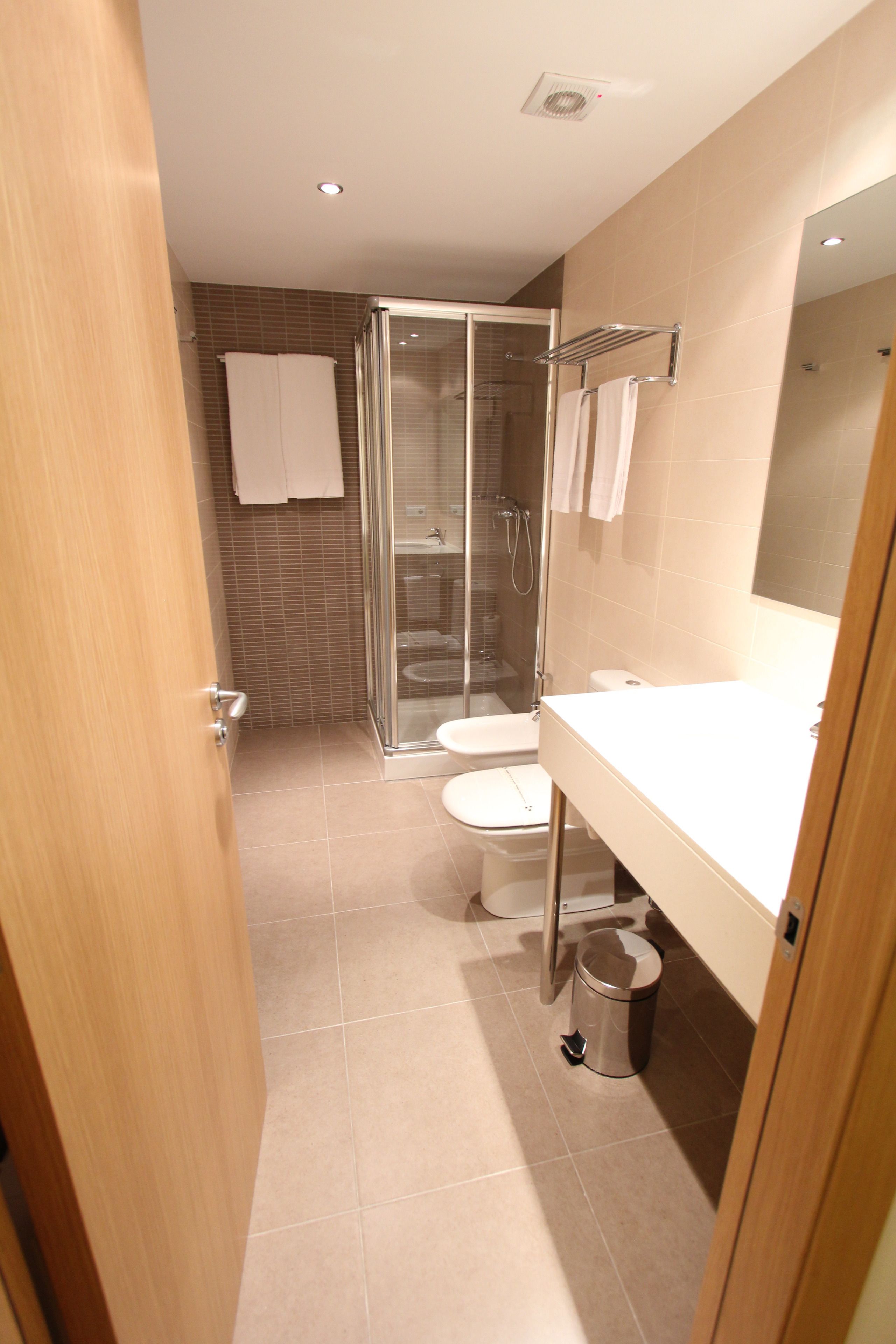 A modern bathroom with a glass shower enclosure, a toilet, and a sink.