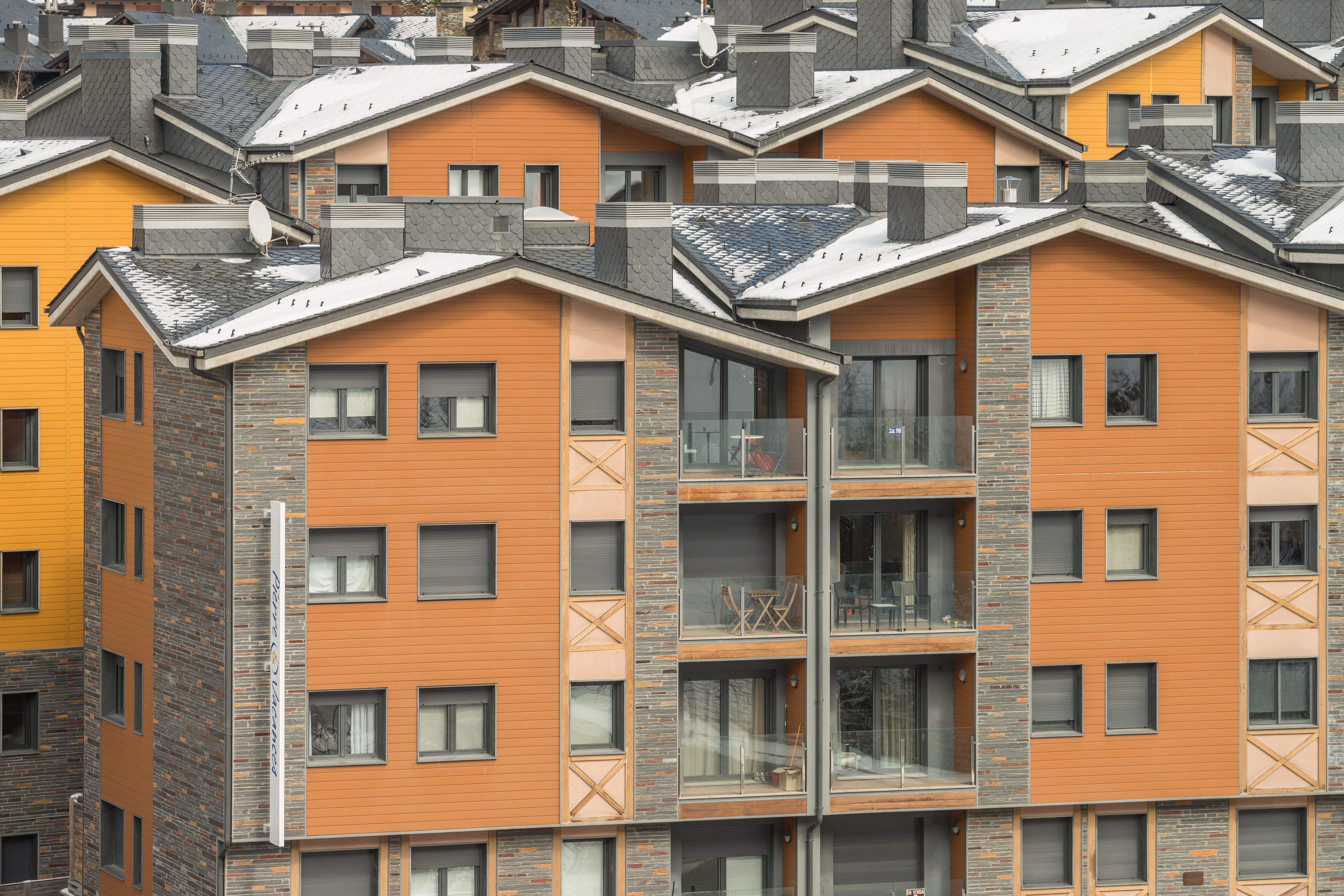Um edifício residencial de vários andares com design arquitetônico moderno, com varandas e grandes janelas.