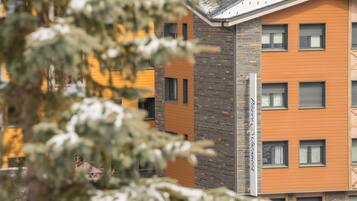 Un immeuble à plusieurs étages, doté d’une façade en briques et de panneaux orange, avec de nombreuses fenêtres et des balcons.