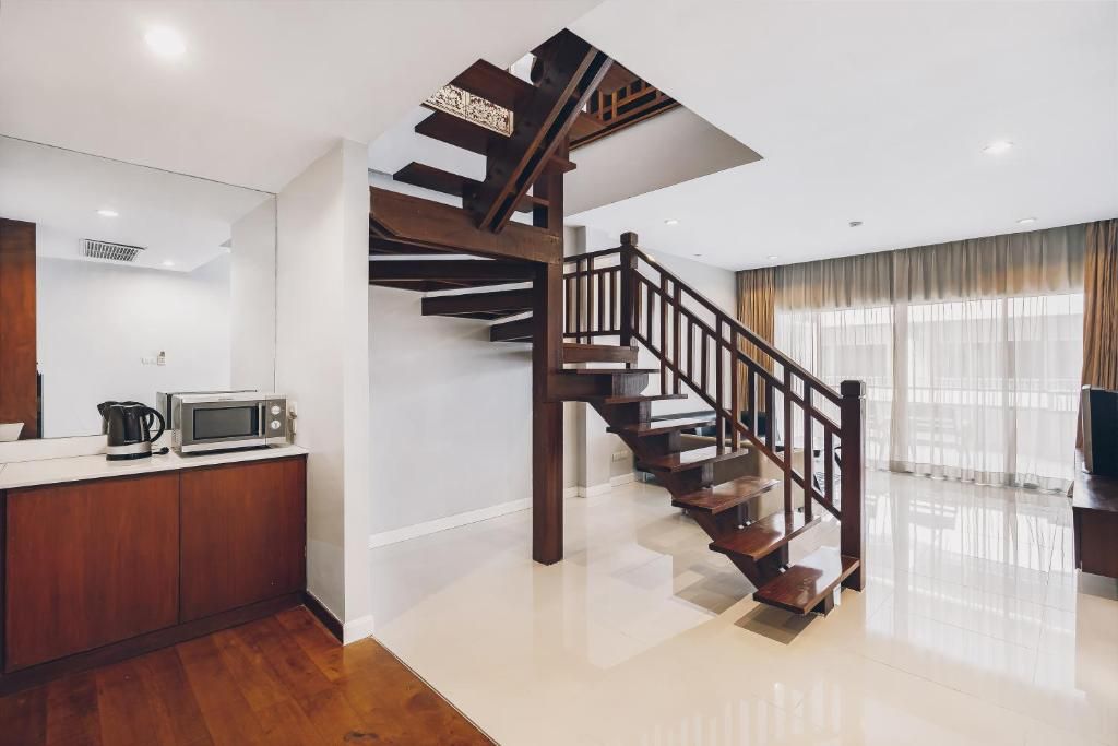 A modern kitchen with a built-in microwave, wooden cabinets, and a stainless steel kettle.