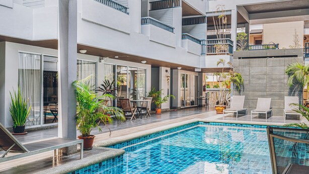 Un hotel moderno con piscina central, zona de estar al aire libre y varios balcones.