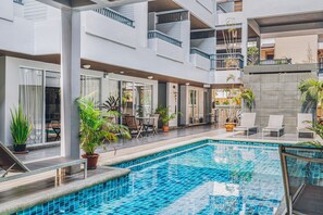 Un hôtel moderne doté d’une piscine centrale, d’un espace extérieur aménagé et de nombreux balcons.