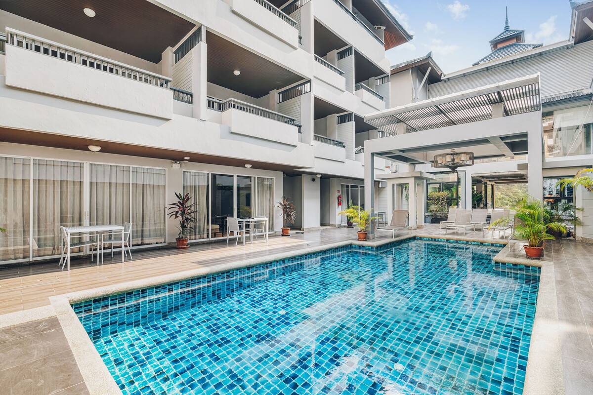 A modern building with a swimming pool, outdoor seating, and a covered patio area.