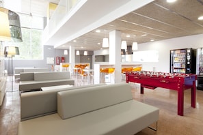 A modern lobby with seating areas, a foosball table, and vending machines. - Residencia Universitaria Resa Manuel Agud Querol (San Sebastián)