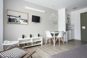 A modern, well-lit room with a dining area, a TV mounted on the wall, and a kitchenette. - Residencia Universitaria Resa Manuel Agud Querol (San Sebastián)