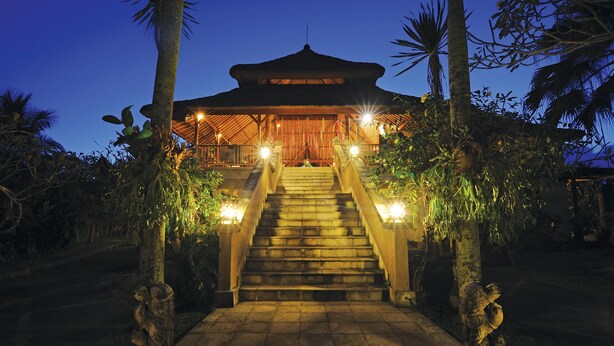 A traditional building with a thatched roof, a staircase leading to the entrance, and stone statues flanking the path. - Bumi Ubud Resort (Ubud)
