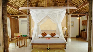 A room with a bed under a canopy, a small table with a chair, and a wall-mounted air conditioner. - Bumi Ubud Resort (Ubud)