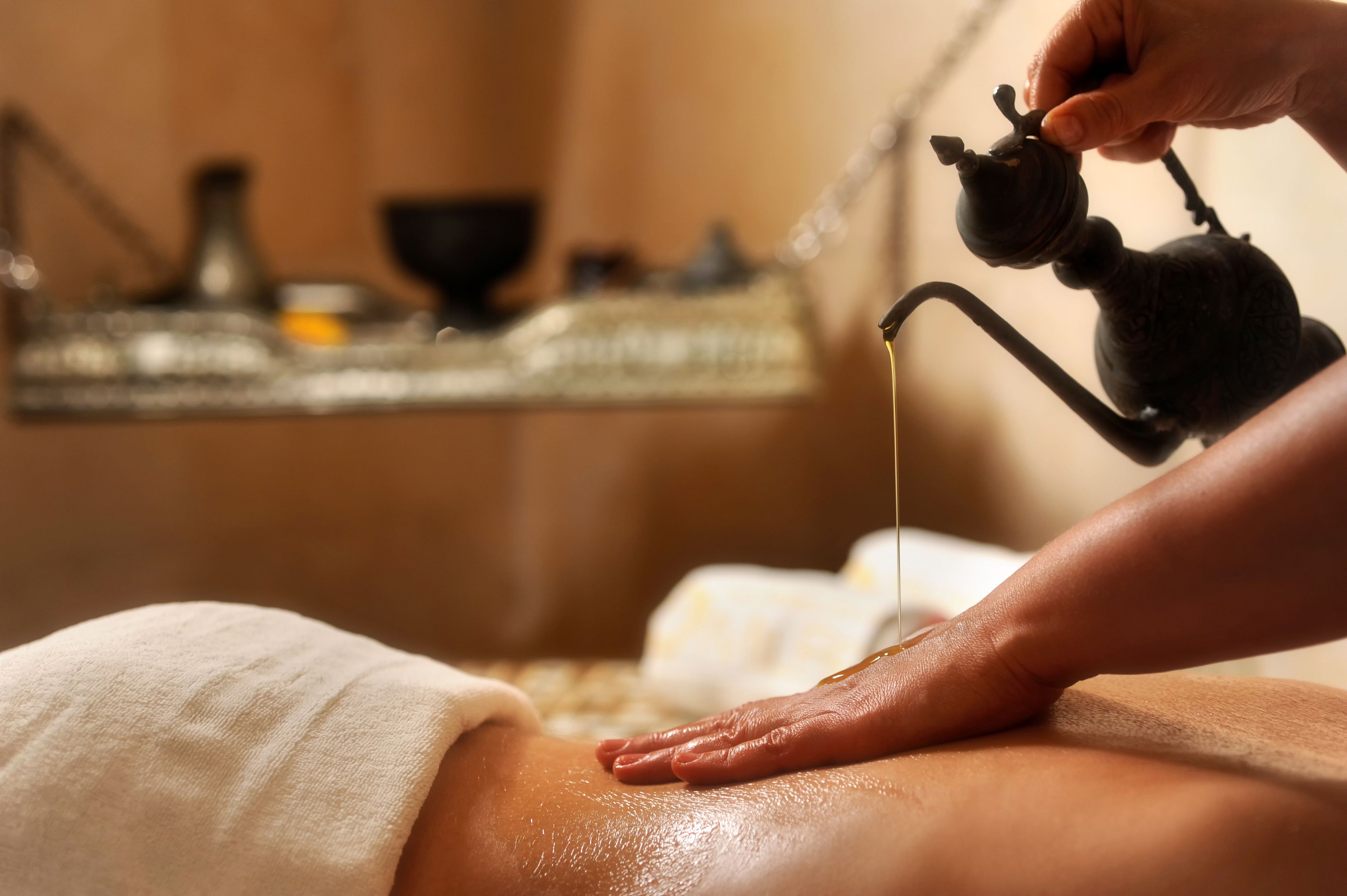 A massage therapy session with a focus on the therapist's hands and a bottle of oil.