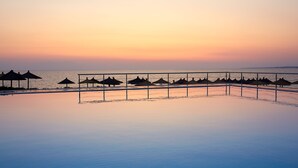 Ein ruhiger Poolbereich mit Sonnenschirmen und einer Brüstung, mit Blick auf das Wasser.