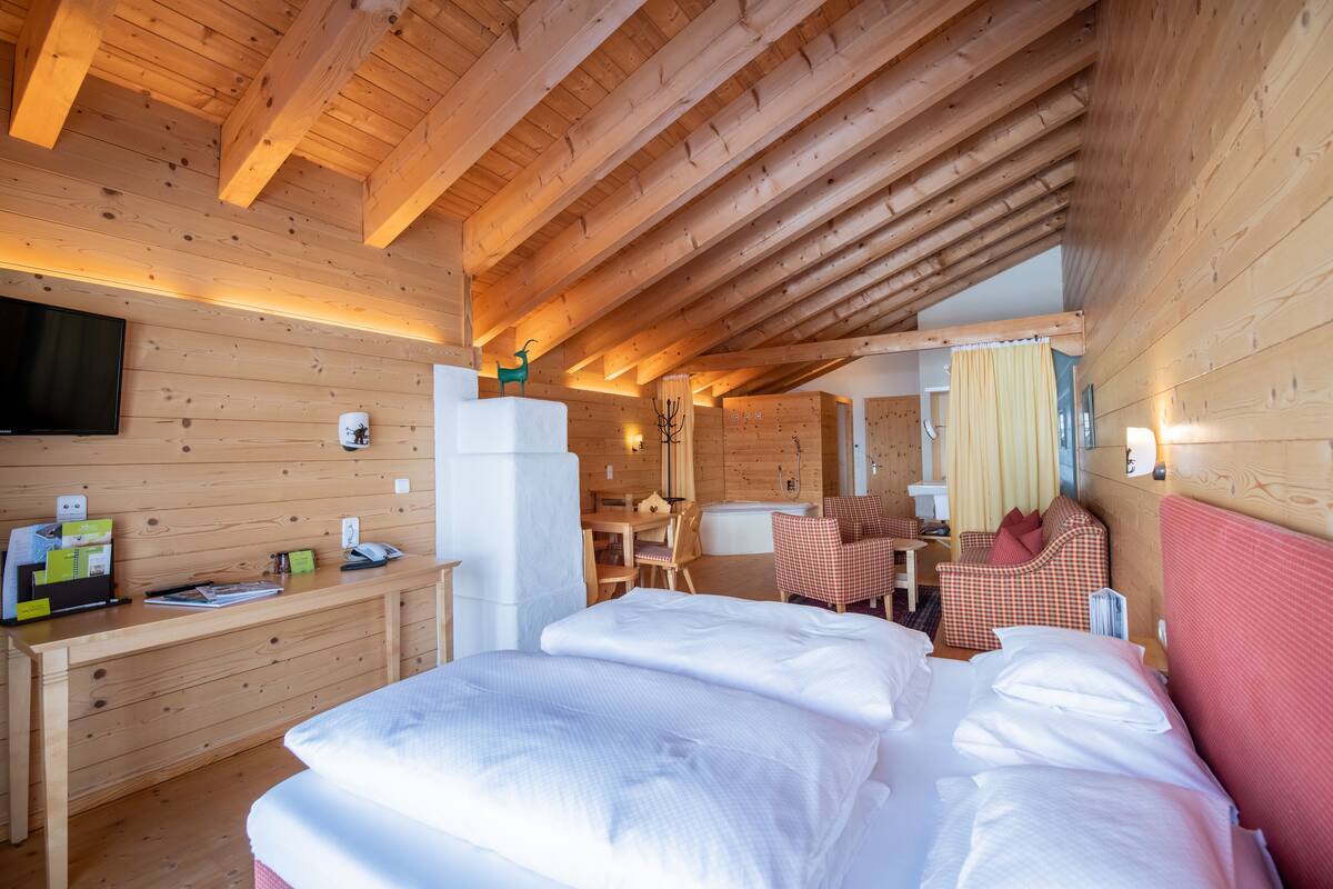 A wooden cabin interior with a bed, desk, and seating area.