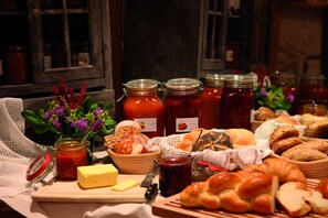 A table with various food items, including bread, cheese, and jars of jam. - Hotel Walserberg (Warth)