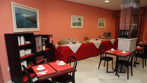 A dining area with tables set for breakfast, a buffet with various food items, and a coffee machine. - Hostal Chaikana (El Puerto de Santa Maria)