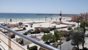 A beachside view with a parking area, beach access, and a tall lighthouse. - Adiafa Hotel (Barbate)