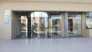 A hotel entrance with a revolving door, a sign for the Adiafa Hotel, and a blue sign indicating a handicap-accessible entrance. - Adiafa Hotel (Barbate)